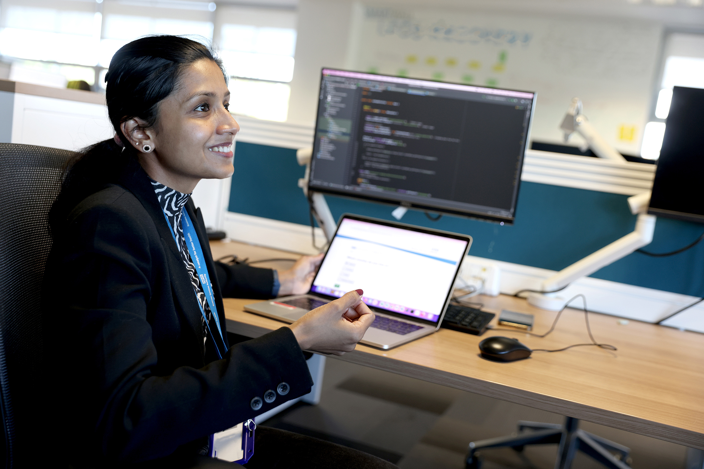 Smiling person in discussion while working at laptop