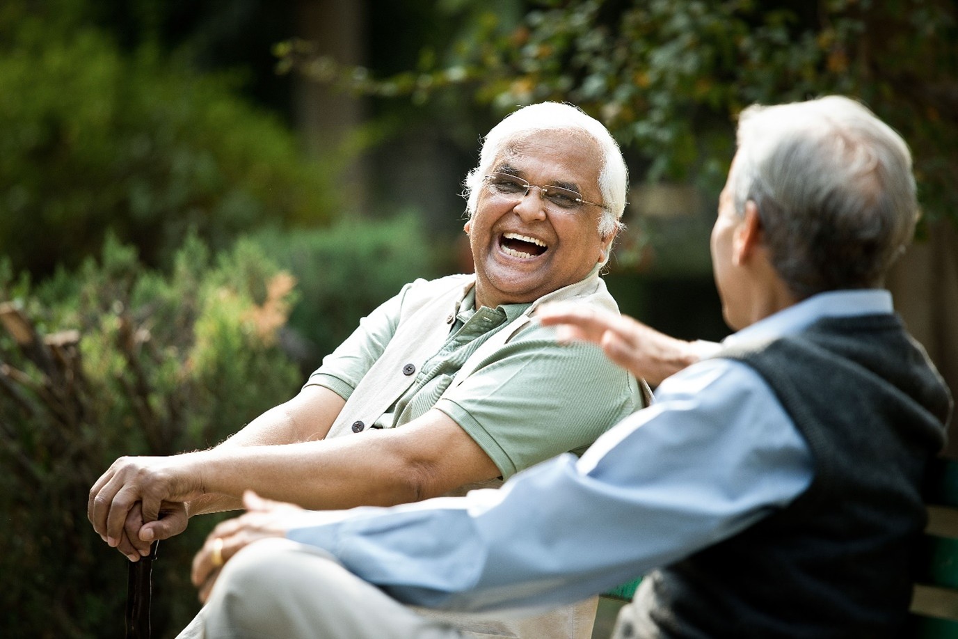 2 men laughing, sitting on park bench
