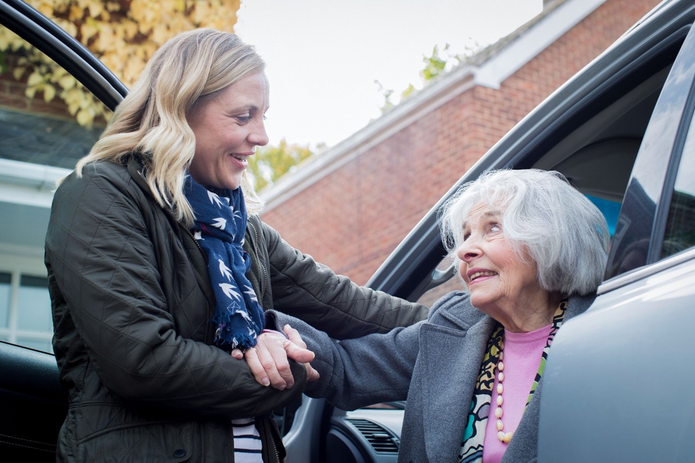 Volunteer helping a lady out of a car